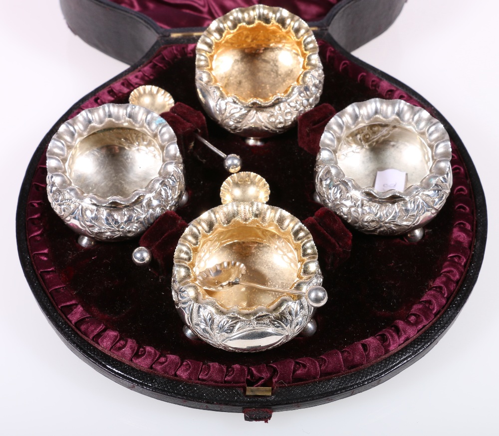 Victorian cased set of four silver salts, on ball feet, with three shell spoons, Birmingham 1888,
