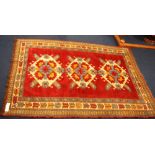 Kazak style rug with three hooked lozenges on a claret ground, 182cm x 129cm.