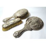 Silver three-piece brush set of Art Nouveau style embossed with a figure and swirling leafage, 1903.