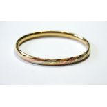 Tri-colour 15ct gold bangle with hinged snap fastening, '585'. Condition Report 13.