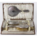 A George V silver five piece dressing table set, comprising four brushes and a hand mirror,