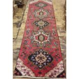 A Persian wool runner, with a geometric design against a red ground,