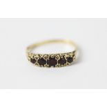 A garnet five stone ring, the five graduated garnets set in yellow metal, indistinctly stamped,