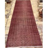 A wool runner, worked with a geometric pattern against a red ground,