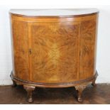 A 1930's walnut demi lune side cabinet, with quarter veneerd door on shell carved cabriole legs,