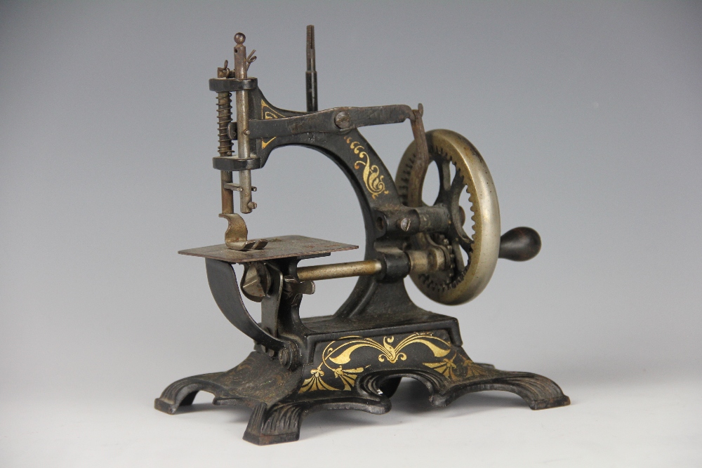 A late 19th century miniature sewing machine, No 23161, cast iron frame with gilt detailing,