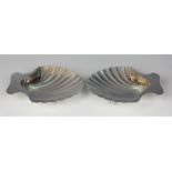 A pair of Tiffany and Co silver butter dishes, each of shell form and raised on two bun feet,