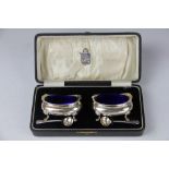 A pair of George V silver salts, with blue glass liners and spoons, in original case,