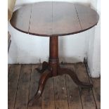 A George II oak tilt top table, with four plank top on a turned column and tripod base,