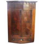 A George III mahogany bow front corner cabinet, with two drawers above a small drawer,