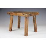 An early 19th century oak milking stool, with rectangular seat on four moulded legs,