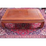 A Chinese hardwood low coffee table, with panelled top on scroll legs,