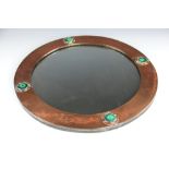 A Liberty & Co copper circular wall mirror, set with four Ruskin style cabochons,