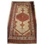 A Caucasian rug, worked with a floral red central medallion against an ivory ground,