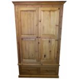 A modern pine two door wardrobe, with base drawer, on plinth base,