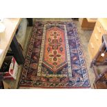 A Caucasian wool rug, worked with a geometric design against a red ground,