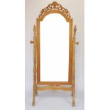 A modern pine cheval mirror, with turned uprights, on carved scroll legs,