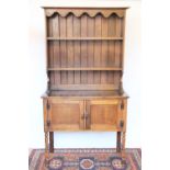 A 1920's oak high back dresser, with two open shelves above two cupboard doors on turned legs,