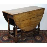 An 18th century oak gate leg table, with semicircular flaps, on turned and block legs,