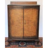 A 1920's walnut cabinet, the bow front revealing three sliding trays,