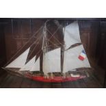 A model of a French yacht, with red painted hull, in glass fronted case,