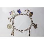 A silver curb link charm bracelet, with a variety of attached charms to include a donkey,