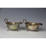 A pair of George V silver sauce boats, with scroll handles on shell case legs, Adie Brothers,