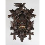 A Black Forest carved wood cuckoo clock, surmounted with a bird,