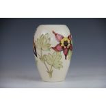 A Moorcroft Aquilaga pattern vase, the purple, red and yellow blooms against a cream ground,