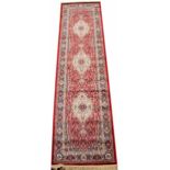 A Kashmir runner, worked with an all over foliate design against a red ground,