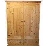 A modern pine two door wardrobe, with two base drawers, on plinth base,