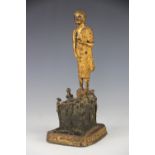 A Tibetan gilt bronze figure of a deity, modelled standing on an altar table, on canted base,