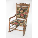 A late 19th century carved beech rocking chair, possibly American, with foliate floral upholstery,