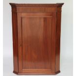 A late George III mahogany hanging corner cabinet, with panelled door,