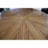 A modern circular dining table, radially veneered in striped zebra type wood, on tapered legs,