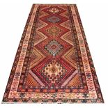 A hand woven wool runner, worked with five foliate panels against a red ground,