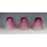 A set of three Art Nouveau graduated cranberry to clear glass light shades,