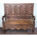 An early 18th century and later carved oak settle, with five panel back above a hinged seat,