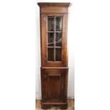 A modern oak corner cabinet, with glazed and panelled door on bracket feet,