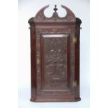 A Victorian carved walnut hanging corner cabinet, with arched cornice and panelled door,