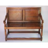 An 18th century style oak settle, with panelled back and seat on turned legs,