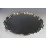 A large silver plated salver, with pie crust border, on three claw and ball feet,