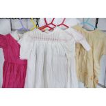 A quantity of assorted vintage dolls outfits, to include dresses, capes, vintage christening gowns,