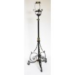 An Arts and Crafts iron and brass oil standard lamp, on scroll tripod base,