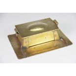 An Arts and Crafts brass desk stand, with sliding lid enclosing two inkwells,