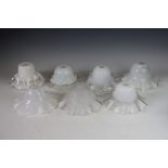 A collection of eight clear and opaque glass lamp shades,