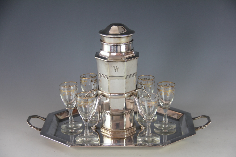 An Art Deco silver plated cocktail shaker and twin handled stand,