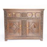 An early 18th century style carved oak cupboard, with two fielded panelled drawers,