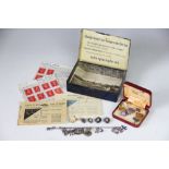 A French tin containing a selection of jewellery, to include; a charm bracelet, earrings, pendants,