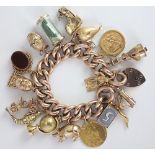 A 9ct gold hollow curb link bracelet with attached padlock clasp, with numerous attached charms,